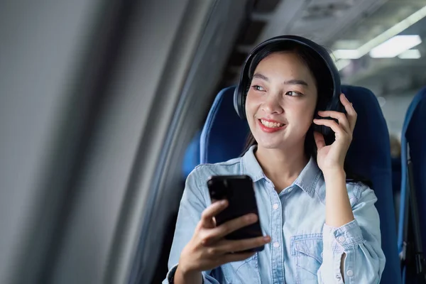 Asian people female person onboard, airplane window, using mobile while on the plane.