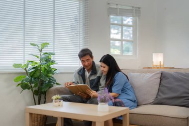 Emekli yaşlı çift evlerindeki kanepede oturup rahatlama kitabı okuyor. Kıdemli Etkinlik Konsepti.