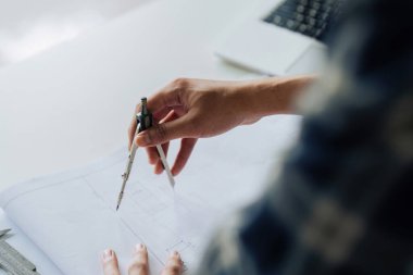 Modern ofiste proje üzerinde çalışan bir inşaat projesinin taslağını çizen mimar.