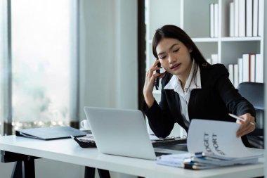 İş kadını telefonda ve ofisteki bilgisayarı kullanıyor. İş kadını profesyonel cep telefonuyla konuşuyor.