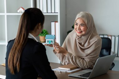 Müslüman emlakçı ev satın alma anlaşmasının şartları hakkında konuşur ve müşteriden sözleşmeyi yasal hale getirmek için belge imzalamasını ister..