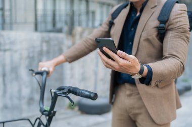 Asyalı genç işadamı şehirde iş seyahatinde akıllı telefon kullanır. Çevre dostu.