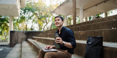 İşadamı bankta oturuyor ve dizüstü bilgisayarla proje üzerinde çalışıyor..