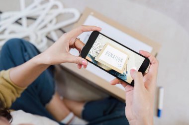 Asyalı kadın, sosyal medyada arkadaşını bağış yapmaya teşvik etmek için bağış kutusunun fotoğrafını çekiyor..