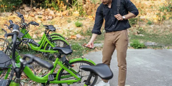 business man holding mobile using bike rental digital phone app scanning qr code to rent electric bicycle in city.