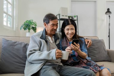 Gülümseyen Kafkasyalı yaşlı çift birlikte cep telefonu kullanıyor..