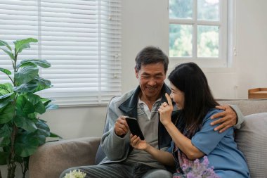 Gülümseyen Kafkasyalı yaşlı çift birlikte cep telefonu kullanıyor..