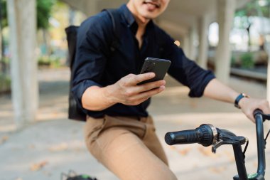 Asyalı genç işadamı şehirde iş seyahatinde akıllı telefon kullanır. Çevre dostu.