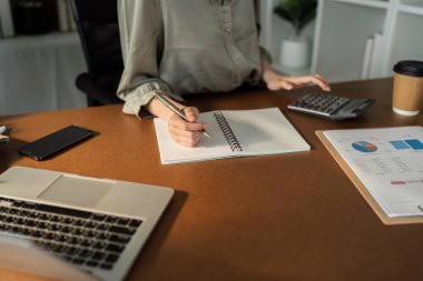 Asyalı iş kadını hesap makinesiyle rapor veriyor. Not al. Finansal rapor yazmayı ya da kâr etmeyi unutma...