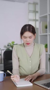 Evdeki stüdyoda dizüstü bilgisayarla çalışan yaratıcı Asyalı genç kadın..
