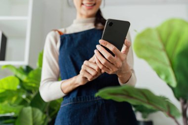 Kadın cep telefonunu tut ve yeni dikilmiş ağacın fotoğrafını çek. Çevre dostu ev.