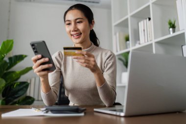 İnternetten alışveriş yapan bir kadın, dizüstü bilgisayarından online ödeme kartı yapıyor..