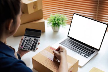 Genç girişimci bir kutuyu bantla mühürlüyor. Nakliyeye, paketlemeye, çevrimiçi satışa, e-ticaret konseptine hazırlık.