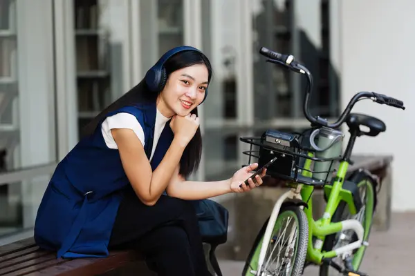 Asian young businesswoman bike to work for eco friendly green energy and use smart phone while commuting in city. Eco friendly.
