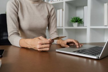 İnternetten alışveriş yapan bir kadın, dizüstü bilgisayarından online ödeme kartı yapıyor..