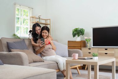 Kutlarım. Sevgi dolu Asyalı yetişkin kız Anneler Günü 'nde annesine hediye paketi ve el yapımı kart vererek sürpriz yaptı..