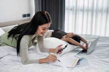 İş adamı, işten eve getirilen bir çocukla ilgilenirken yatakta evrak hazırlıyor..