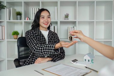 Emlakçı, sözleşme belgesini başarılı bir şekilde imzaladıktan sonra ev anahtarını istemciye verdi.