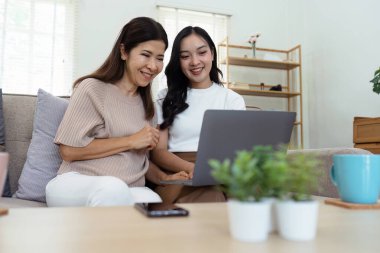 Anne ve yetişkin kız kanepede birlikte oturuyorlar, anne ve kız internet sitesinde birlikte sörf yapıyorlar..