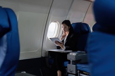 Uçakta tabletle çalışan Asyalı güzel bir iş kadını. çalışma, seyahat, iş konsepti.