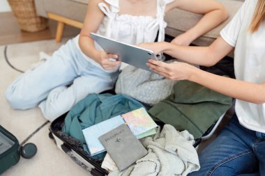 Arkadaşları seyahat acentesinde tatil için tablet kullanıyor ya da internet üzerinden otel rezervasyonu yaptırıyor ve giysilerini bavula koyup seyahat tatili planlıyorlar.