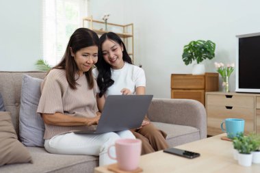 Anne ve yetişkin kız kanepede birlikte oturuyorlar, anne ve kız internet sitesinde birlikte sörf yapıyorlar..