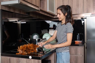 Ev hanımı evi temizler ve lavaboda bulaşıkları yıkar. Ev temizleme kavramı.