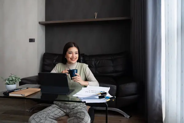 亚洲女商人放松下来 在家里的笔记本电脑上工作 在家工作的概念 免版税图库照片