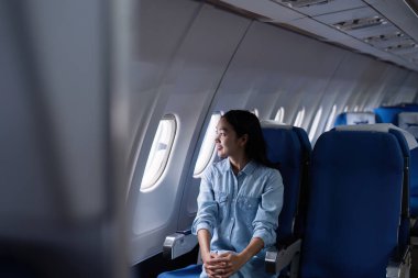 Uçakta cep telefonu kullanan Asyalı bir kadın var..