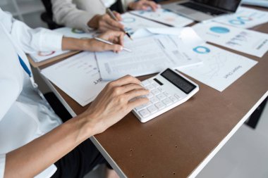 İş muhasebe defteri, iş veri özeti raporunu, muhasebe belgesini ve ofisteki dizüstü bilgisayarını hesaplamak için hesap makinesiyle çalışıyor..