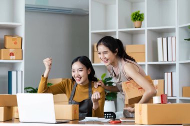 Çevrimiçi Satış Başarısını Kutlayan Heyecanlı Kadın Girişimciler. Dizüstü bilgisayar kullanan genç bir girişimci. Nakliyeye, çevrimiçi satışa, e-ticaret konseptine hazırlık.