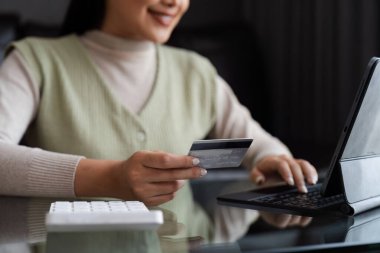 Evde online alışveriş, ödeme, satın alma ve çevrimiçi alışveriş kavramı için kredi kartı ve tablet kullanan genç kadın.