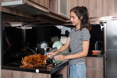 Ev hanımı evi temizler ve lavaboda bulaşıkları yıkar. Ev temizleme kavramı.