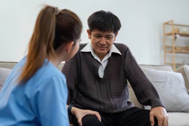 fizyoterapist ya da bakıcı yaşlı bir adamın dizlerini esnetmesine yardım ediyor..