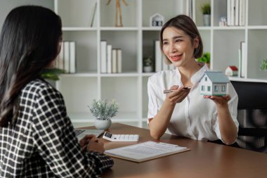 Emlakçı ev satın alma anlaşmasının şartları hakkında konuştu ve müşteriden belgeleri imzalamasını istedi..
