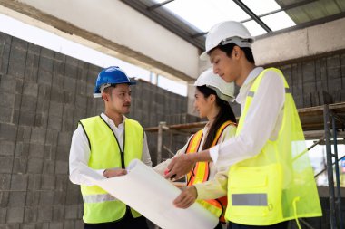 Mühendislerden oluşan bir ekip bina planlarına bakıyor ve bunları inşaat binasında tartışıyor..