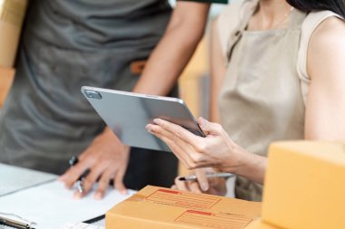 Girişimciler, modern e-ticaret uygulamalarını temsil ederek çevrimiçi siparişleri ve envanteri yönetmek için dijital tablet kullanıyorlar.