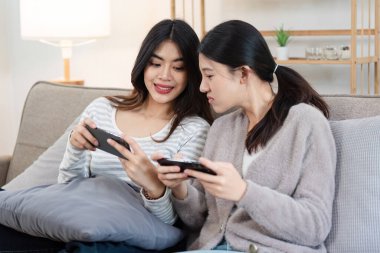 LGBT çifti evde kaliteli zaman geçiriyorlar, kanepede dinleniyorlar, ve eğlenceli aktiviteler yapıyorlar, modern yaşam tarzını ve aşkı kucaklıyorlar..