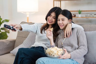 LGBT couple enjoying a cozy evening at home, watching TV and sharing popcorn, showcasing love and modern lifestyle. clipart