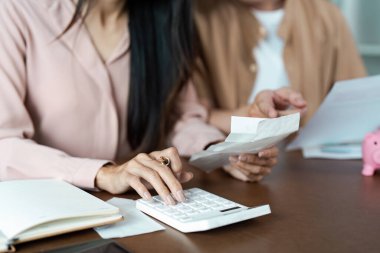 Bütçelerini ve giderlerini karşılamak için hesap makinesi ve belgeler kullanan çift evde mali durumlarını planlıyorlar..