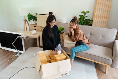 Lezbiyen çift yeni evlerinde kutuları açıyor. Aşkı, birlikteliği sembolize ediyorlar ve modern bir yaşam alanında yeni bir başlangıç yapıyorlar..