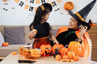 Anne ve kızı evde eğleniyor. Mutlu aile Cadılar Bayramı için hazırlanıyor.