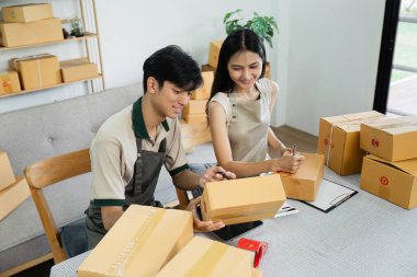 İki genç girişimci, çevrimiçi küçük işletmelerinin bir parçası olarak, paketleme ve nakliyat ürünleri hazırlamak için bir ev ofisinde birlikte çalışıyorlar..