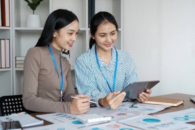 İş kadını meslektaşlar, görev yerindeki tablet hakkındaki işbirliği brifinginde bilgi tartışıyor.