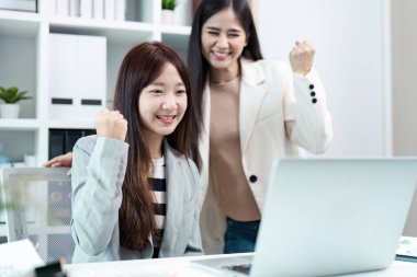 Modern bir ofiste iki kadın başarılı bir iş birliğini, takım çalışmasını ve başarısını kutluyor..