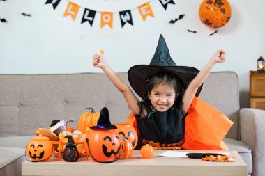 Cadı gibi giyinmiş neşeli bir çocuk Cadılar Bayramı 'nı balkabakları ve ev dekorasyonuyla kutluyor..