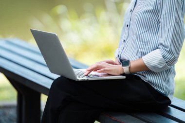 Açık havada dizüstü bilgisayarda çalışan dijital bir göçebe, doğal ortamda uzaktan çalışmanın esnekliğini ve özgürlüğünü gösteriyor..
