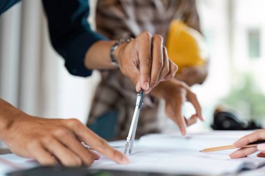 Mimarların ellerinin planda pusula kullanarak yakın plan çekimleri, modern ofis ortamında bir proje üzerinde işbirliği.