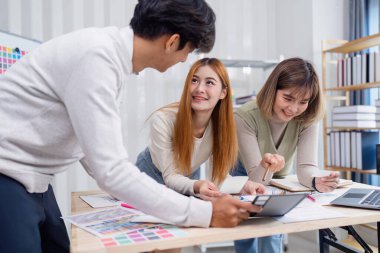 UX UI projesinde birlikte çalışan çeşitli tasarımcılardan oluşan bir ekip, fikirleri tartışıyor ve çağdaş bir ofis ortamında tasarım prototiplerini gözden geçiriyorlar..