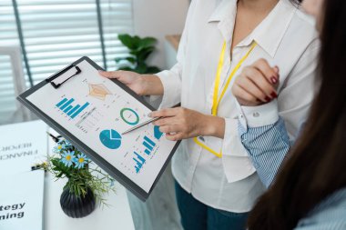 Modern bir ofis ortamında strateji planlama oturumunda veri grafikleri ve grafikleri tartışan iki iş adamı.